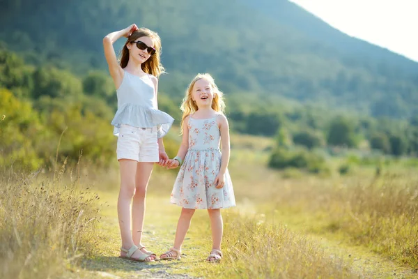Due giovani sorelle carine che ridono e si abbracciano nella calda e soleggiata giornata estiva durante le vacanze in famiglia in Grecia — Foto Stock