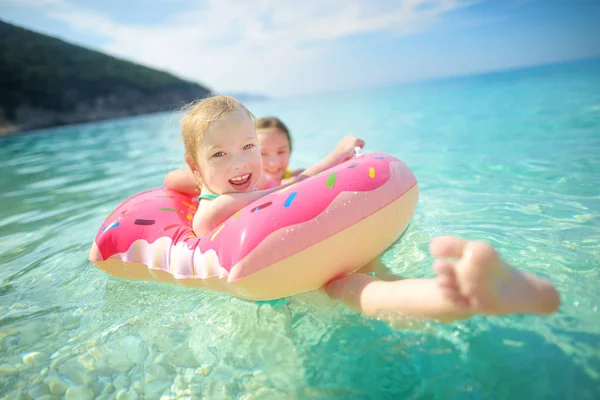 可爱的姐妹漂浮在玩具环在 Myrtos 凯法利尼亚最著名和最美丽的海滩 一个大海岸与绿茶水和白色粗糙的沙子 希腊头孢罗尼亚 — 图库照片