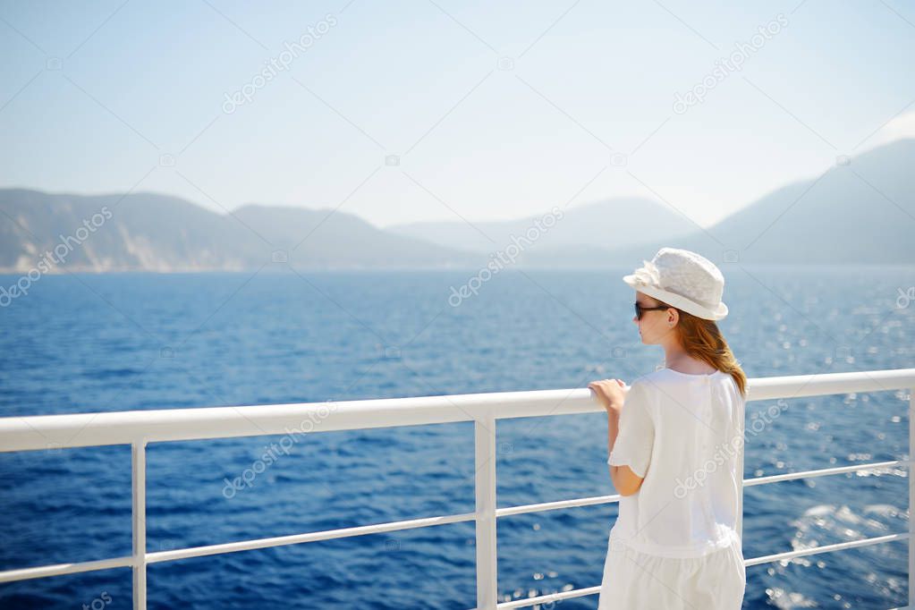 Adorable young girl enjoying ferry ride staring at the deep blue sea. Child having fun on summer family vacation in Greece. Kid sailing on a boat.