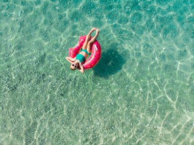 Oyuncak yüzük Myrtos beach, Kefalonia en güzel plaj, gezinti su ve beyaz kaba kum ile büyük bir sahil üzerinde yüzen sevimli genç kız görünümünü hava üstünü. Kefalonia, Yunanistan.