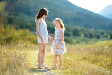 Gülüyor ve aile tatil sırasında sıcak ve güneşli yaz gününde Yunanistan'da sarılma iki sevimli genç kız