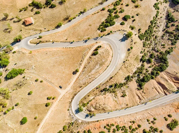 Luftaufnahme einer Serpentinenstraße, die sich zwischen Bergen in Westgriechenland schlängelt. eine kurvenreiche Straße, die sich im Peloponnes steil den Berg hinauf schlängelt, Griechenland. — Stockfoto
