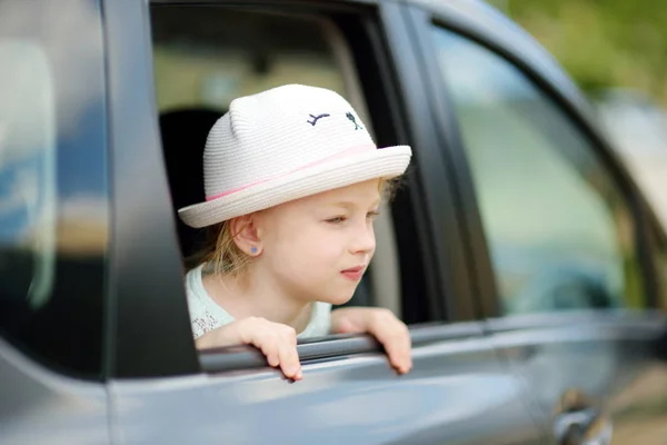 面白い少女は楽しみにして今後の敢行や旅行のための車の窓を彼女の頭を突き出しています — ストック写真