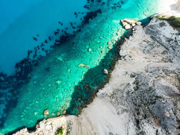 急な崖に囲まれた透明なターコイズ ブルーの海でケファロニア島の絵のようなギザギザの海岸線のトップダウンの風光明媚な空中. — ストック写真