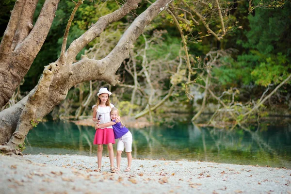 Zagoria, Yunanistan için aile tatil sırasında sıcak ve güneşli yaz gününde Voidomatis nehir kenarında eğleniyor iki sevimli genç kız kardeş — Stok fotoğraf