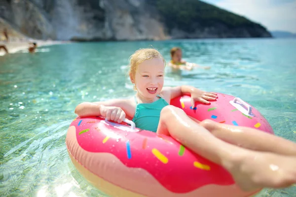 可爱的年轻女孩漂浮在玩具环在 Myrtos 凯法利尼亚最著名和最美丽的海滩 一个大海岸与绿茶水和白色粗糙的沙子 希腊头孢罗尼亚 — 图库照片