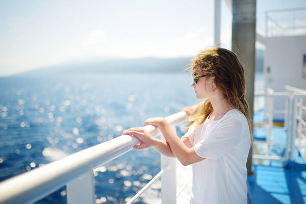 Очаровательная молодая девушка наслаждается паромной прогулкой, глядя на глубокое синее море. Ребенок, отдыхающий на летний семейный отдых в Греции. Мальчик, плывущий на лодке.