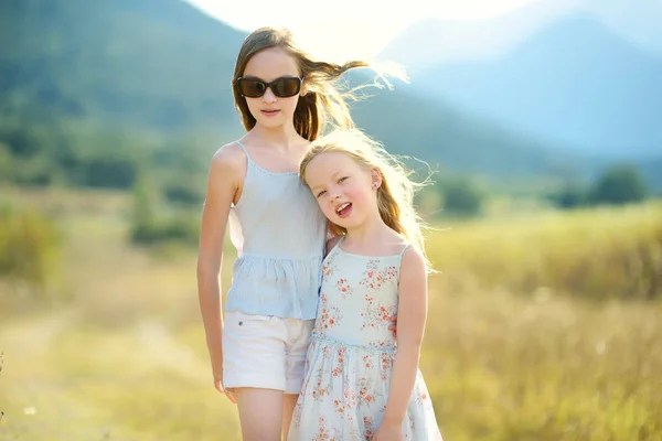 Zwei süße junge Schwestern lachen und umarmen sich an einem warmen und sonnigen Sommertag während eines Familienurlaubs in Griechenland — Stockfoto