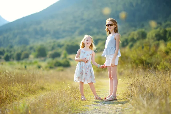 Két aranyos fiatal nővér nevetett, és átölelte a meleg és napos nyarán nap során családi vakáció Görögországban — Stock Fotó