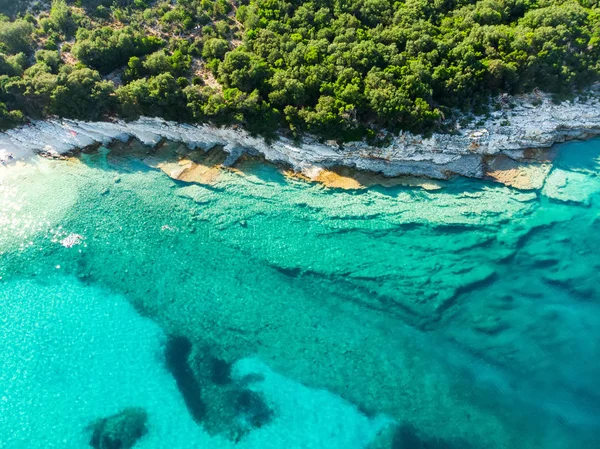 Luftaufnahme vom Strand von Emplisi, einem malerischen steinigen Strand in einer abgelegenen Bucht, mit klarem Wasser, das zum Schnorcheln beliebt ist. kleiner kieselstrand in der nähe von fiscardo stadt kefalonia, griechenland. — Stockfoto