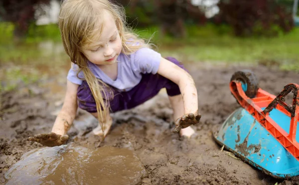 日当たりの良い夏の日に大きな濡れた泥の水たまりで遊んで面白い女の子 粘性土で掘りながら汚れた得ることの子 厄介なゲーム アウトドア — ストック写真