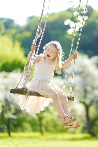 可爱的小女孩在阳光明媚的春天 在户外盛开的老苹果树花园荡秋千上玩得很开心 儿童春季户外活动 — 图库照片