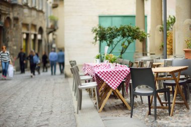 İtalya'nın Bergamo şehrinde güzel bir şekilde dekore edilmiş küçük açık hava restoran masaları