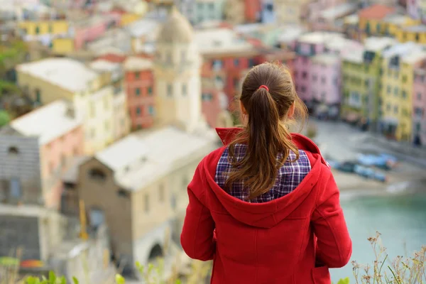 Ung kvinnlig turist njuter av utsikten över Vernazza, en av de fem hundra år gamla byarna i Cinque Terre, som ligger på den oländiga nordvästra kusten av italienska rivieran, Italien. — Stockfoto