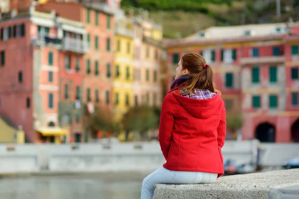 Ung kvinnlig turist njuter av utsikten över Vernazza, en av de fem hundra år gamla byarna i Cinque Terre, som ligger på den oländiga nordvästra kusten av italienska rivieran, Italien. — Stockfoto