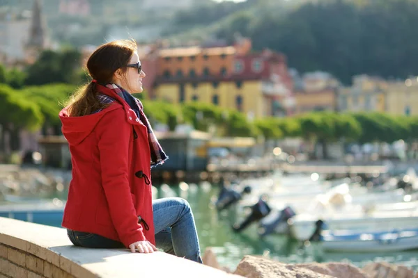 Ung kvinnlig turist njuter av utsikten över små båtar och fiskebåtar i marinan i Lerici stad, som ligger i provinsen La Spezia i Ligurien, Italien. — Stockfoto