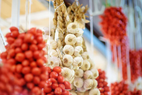 Trossen van biologische knoflook en cherry tomaten verkocht op een marktplaats in Genua, Italië — Stockfoto
