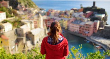 İtalyan Riviera, İtalya 'nın engebeli kuzeybatı kıyısındaki Cinque Terre' nin beş yüz yıllık köylerinden biri olan Vernazza 'nın keyfini çıkaran genç bir kadın turist..