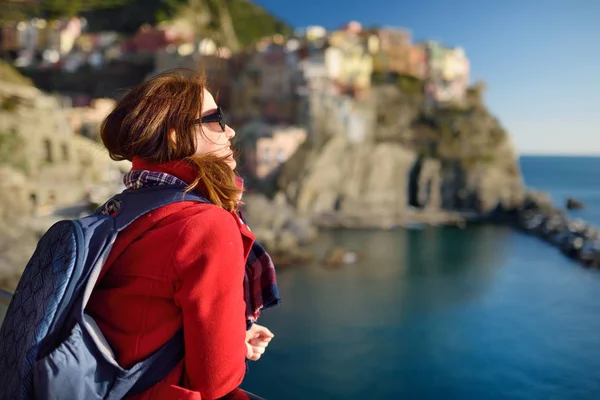 Ung kvinnlig turist njuter av utsikten över Manarola, en av de fem hundra år gamla byarna i Cinque Terre, som ligger på den oländiga nordvästra kusten av italienska rivieran, Italien. — Stockfoto