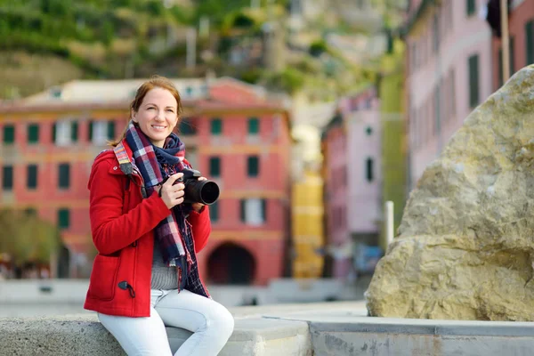 Ung kvinnlig turist njuter av utsikten över Vernazza, en av de fem hundra år gamla byarna i Cinque Terre, som ligger på den oländiga nordvästra kusten av italienska rivieran, Italien. — Stockfoto