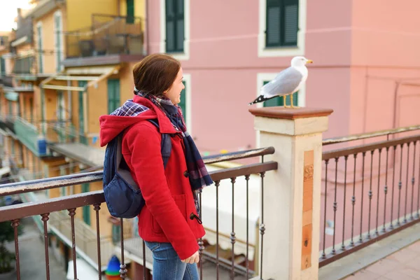 Ung kvinnlig turist njuter av utsikten över Manarola, en av de fem hundra år gamla byarna i Cinque Terre, som ligger på den oländiga nordvästra kusten av italienska rivieran, Italien. — Stockfoto