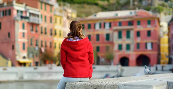 Ung kvinnlig turist njuter av utsikten över Vernazza, en av de fem hundra år gamla byarna i Cinque Terre, som ligger på den oländiga nordvästra kusten av italienska rivieran, Italien. — Stockfoto