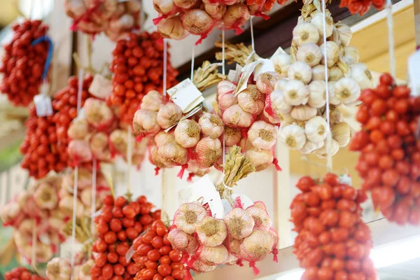 Trossen van biologische knoflook en cherry tomaten verkocht op een marktplaats in Genua, Italië — Stockfoto