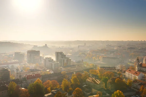 Bella scena nebbiosa Vilnius città in autunno con fogliame arancione e giallo. Aerea vista mattina presto . — Foto Stock