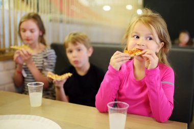 Kapalı restoran veya kafede pizza dilimleri yemek üç sevimli komik kardeşler.