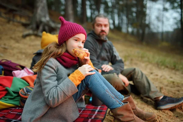Nette kleine Schwestern und ihr Vater picknicken an einem kalten Herbsttag am Lagerfeuer. Kinder haben Spaß am Lagerfeuer. Zelten mit Kindern im Herbstwald. — Stockfoto