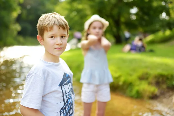 Brother and sister having fun together on warm and sunny summer day in city park. Cute siblings having a good time exploring nature. — Stock Photo, Image