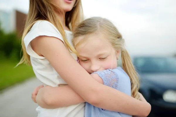 Dos adorables hermanas riendo y abrazándose en un cálido y soleado día de verano en una ciudad . —  Fotos de Stock