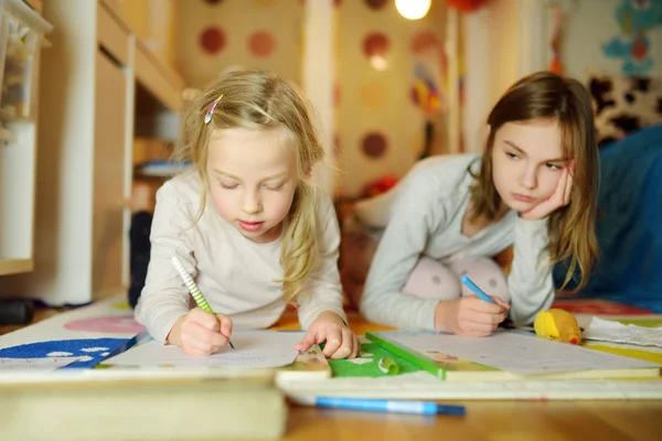 Deux jolies petites sœurs écrivant des lettres ensemble à la maison. Sœur aînée aidant jeune avec ses devoirs . — Photo