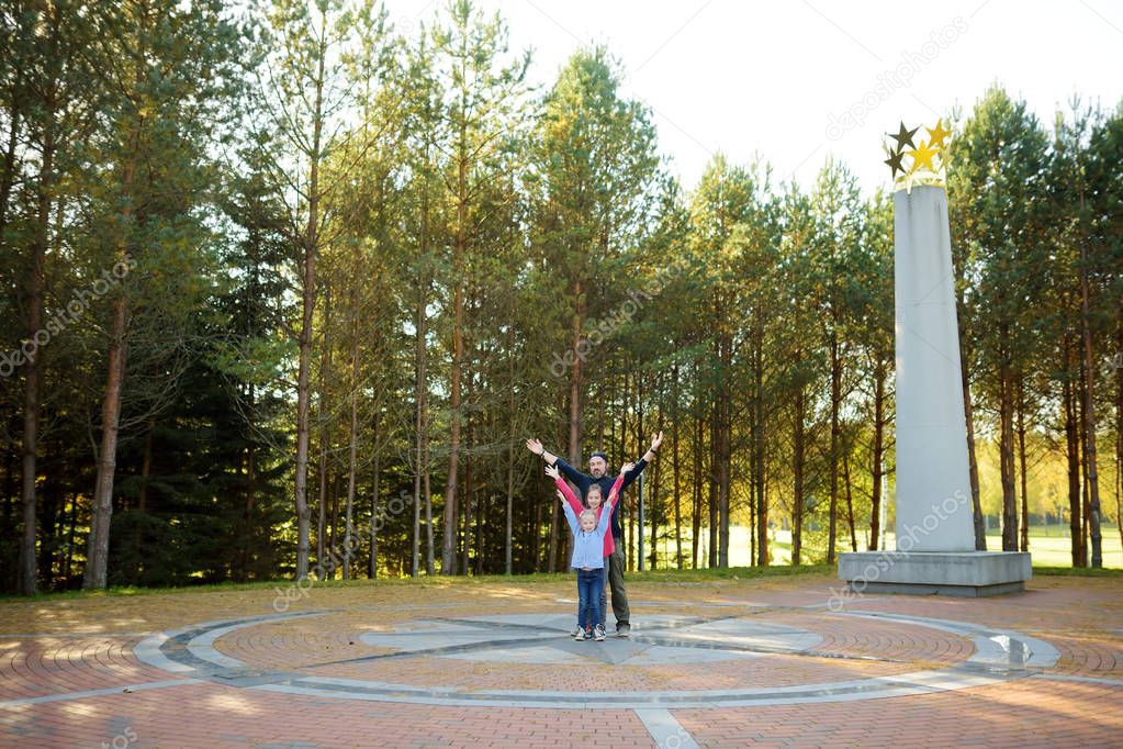 Young father and two kids having fun at the Geographical Centre of Europe, located in Lithuania