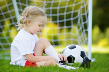 Sevimli küçük futbolcu güneşli yaz gününde bir futbol oyunu oynarken eğleniyor. Çocuklar için spor aktiviteleri.