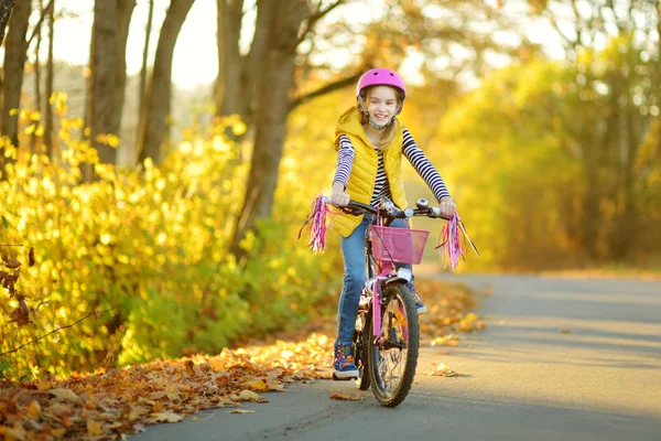 Adorabile ragazza in bicicletta in un parco cittadino nella soleggiata giornata autunnale. Tempo libero famiglia attiva con i bambini . — Foto Stock