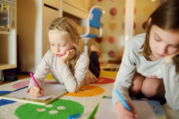 Två söta små systrar skriver brev tillsammans hemma. Äldre syster hjälpa unge med hennes läxor. — Stockfoto