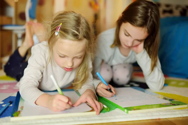 Två söta små systrar skriver brev tillsammans hemma. Äldre syster hjälpa unge med hennes läxor. — Stockfoto