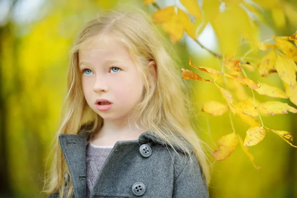 Schattig jong meisje plezier op mooie herfst dag. Gelukkig kind spelen in herfst Park. Kid verzamelen gele val loof. — Stockfoto