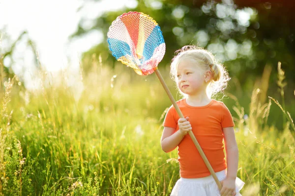 Adorable niñita atrapando mariposas y bichos con su red de pala. Niño explorando la naturaleza en el soleado día de verano . — Foto de Stock