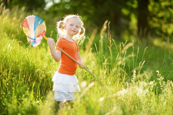 Sevimli küçük kız onu kepçe-net ile kelebekler ve böcek yakalamak. Güneşli yaz gününde doğayı keşfeden çocuk. — Stok fotoğraf