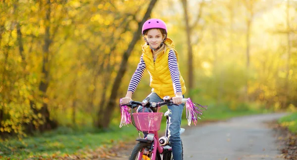 晴れた秋の日に都市公園で自転車に乗って愛らしい若い女の子。子供とのアクティブな家族のレジャー. — ストック写真