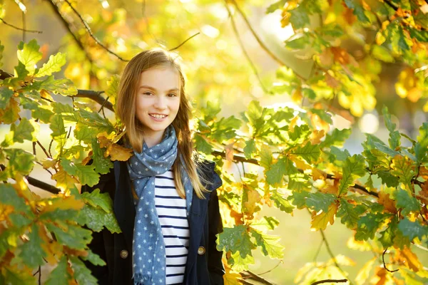 Adorable jeune fille qui s'amuse le beau jour d'automne. Joyeux enfant jouant dans le parc d'automne. Enfant ramassant feuillage jaune automne . — Photo