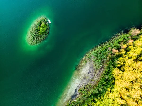Вид сверху с воздуха на маленький остров. Вид с высоты птичьего полета на красивые зеленые воды озера Гела в окружении сосновых лесов . — стоковое фото