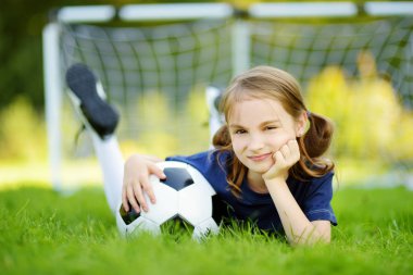 Sevimli küçük futbolcu güneşli yaz gününde bir futbol oyunu oynarken eğleniyor. Çocuklar için spor aktiviteleri.