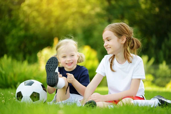 Dos monas hermanitas divirtiéndose jugando un partido de fútbol en el soleado día de verano. Actividades deportivas para niños . —  Fotos de Stock