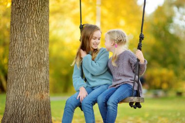 Sevimli genç kız güneşli sonbahar parkta bir salıncak ta eğleniyor. Bir şehirde aile hafta sonu.