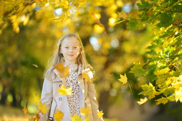 Schattig jong meisje plezier op mooie herfst dag. Gelukkig kind spelen in herfst Park. Kid verzamelen gele val loof. — Stockfoto