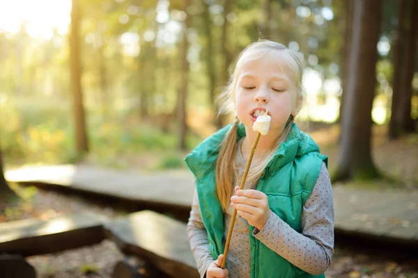 모닥불에 막대기에 마시멜로를 구이 사랑스러운 어린 소녀. 캠프 화재에서 재미를 가진 아이. 가을 숲에서 아이들과 함께 캠핑. — 스톡 사진