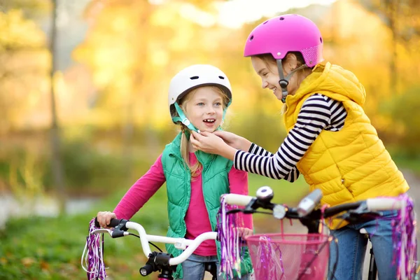 Cute little sisters riding bikes in a city park on sunny autumn day. Active family leisure with kids. — Stock Photo, Image